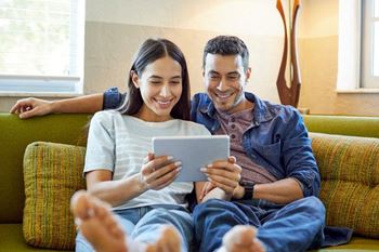 Couple on couch viewing a tablet together.